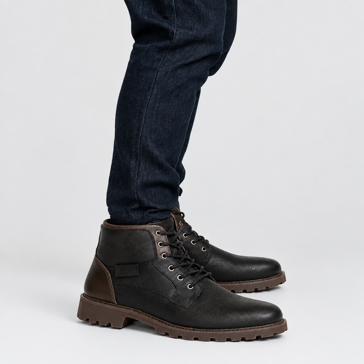 Bottines homme noires, vue de profil en mouvement avec semelle crantée marron visible