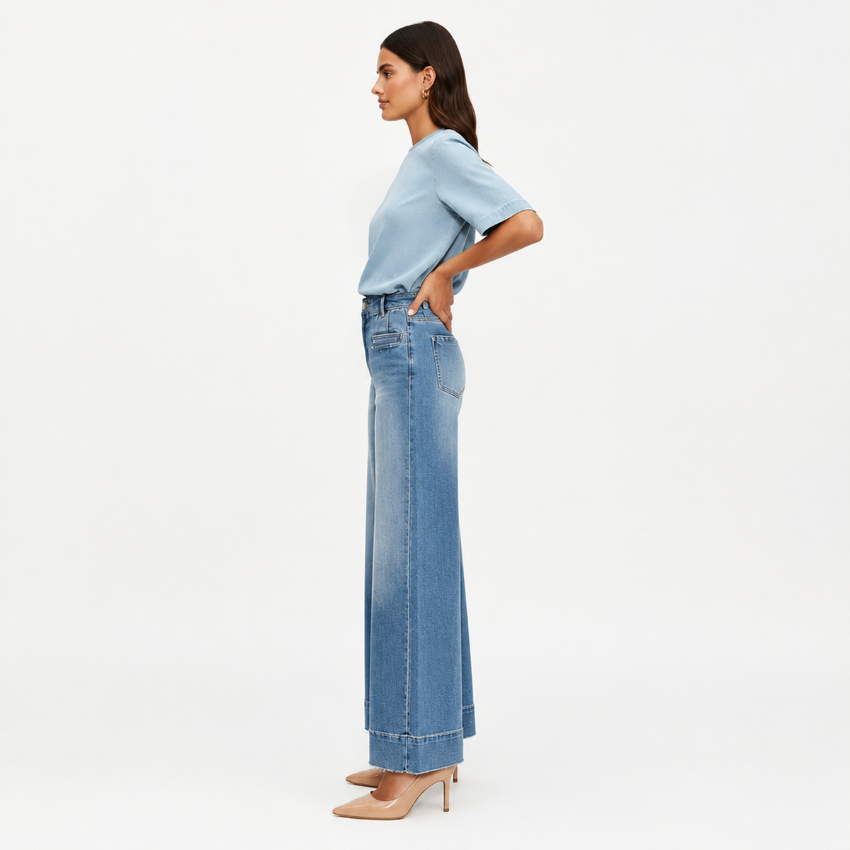 Jean large taille haute en denim bleu clair, vue de profil illustrant la coupe ample des jambes et l'ourlet effiloché