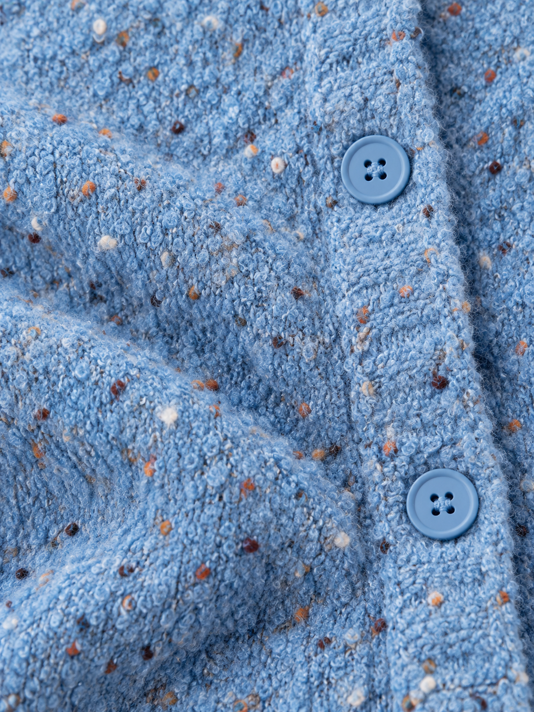 Zoom sur la texture de la maille mouchetée en laine aux détails colorés