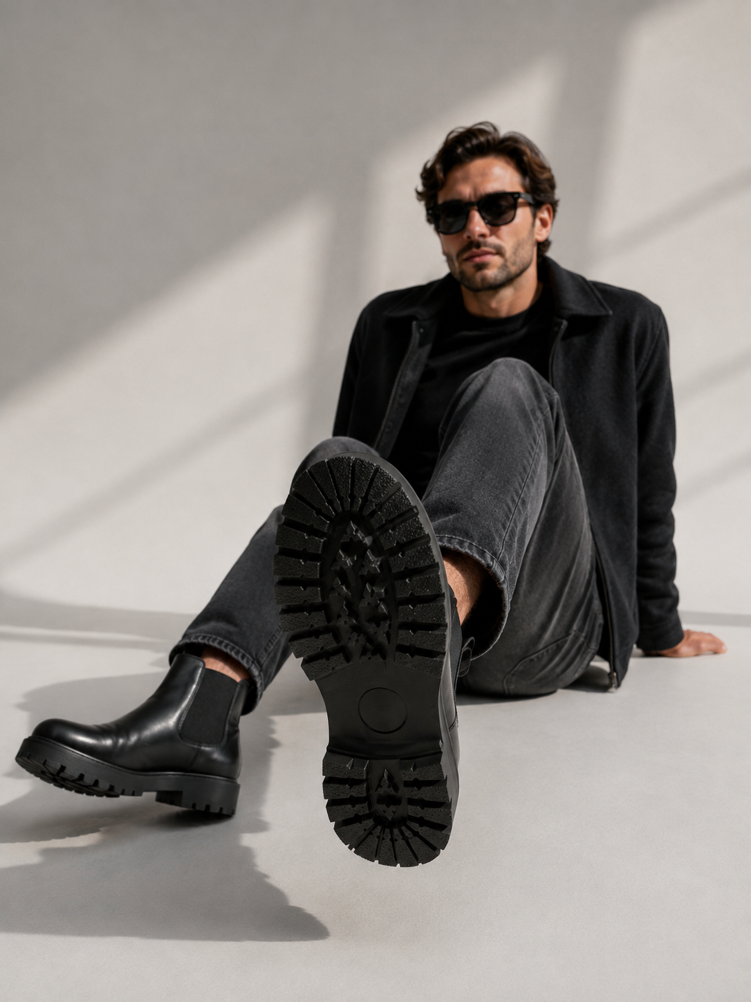 Modèle assis portant les bottines Chelsea chunky homme, semelle crantée visible