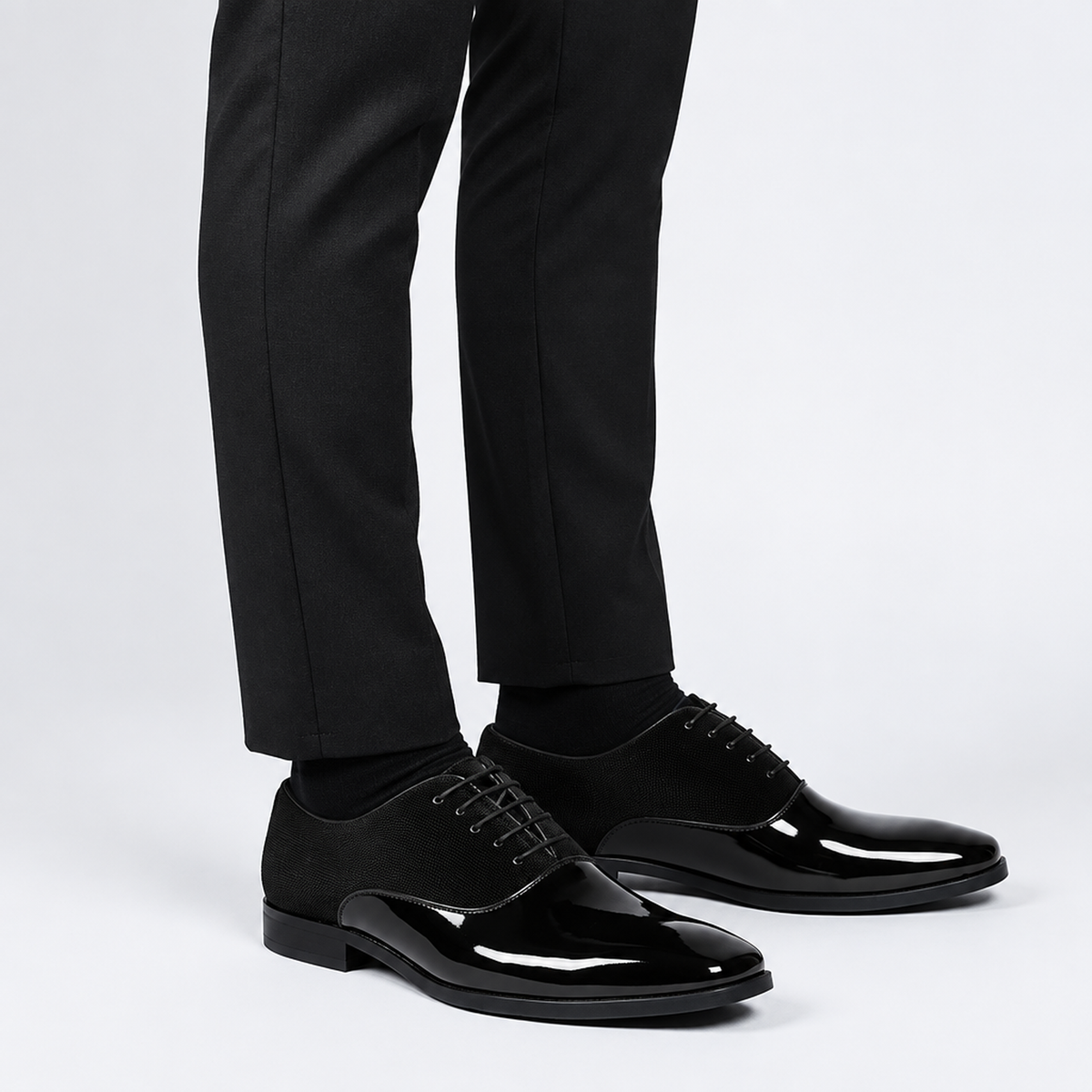 Chaussure habillée vernie noire homme, vue de trois-quarts portée avec pantalon de costume, cuir verni brillant