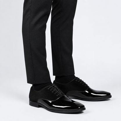 Chaussure habillée vernie noire homme, vue de trois-quarts portée avec pantalon de costume, cuir verni brillant