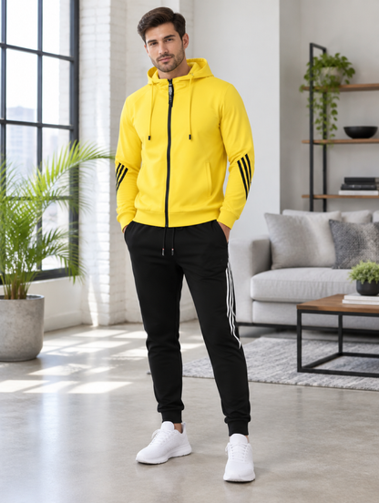 Homme portant l'ensemble jogging jaune à capuche, veste zippée et pantalon noir bandes contrastées, en extérieur