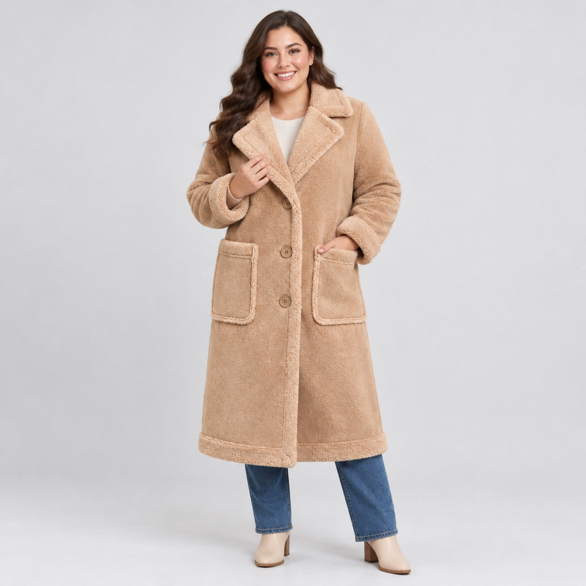 Femme ronde souriante portant le manteau long grande taille en velours aspect suède, photo lifestyle en studio