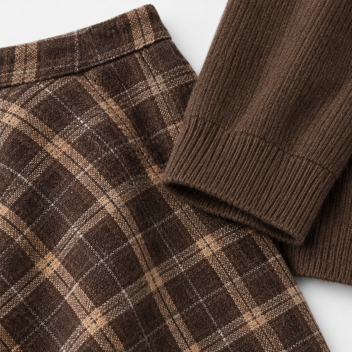 Gros plan sur la maille du pull et le tissu à carreaux de la jupe crayon, détail matière