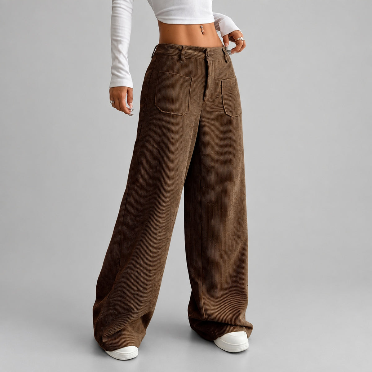 Détail de la taille haute et des poches du pantalon en velours côtelé coloris brun, fond studio neutre
