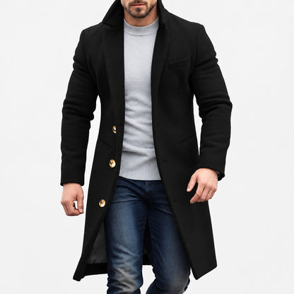 Manteau long homme noir à boutons dorés porté sur un pull gris, vue de face