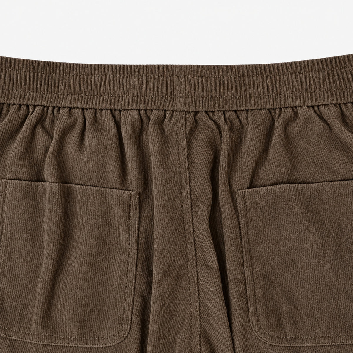 Gros plan sur la taille élastique et les poches arrière du pantalon en velours côtelé marron